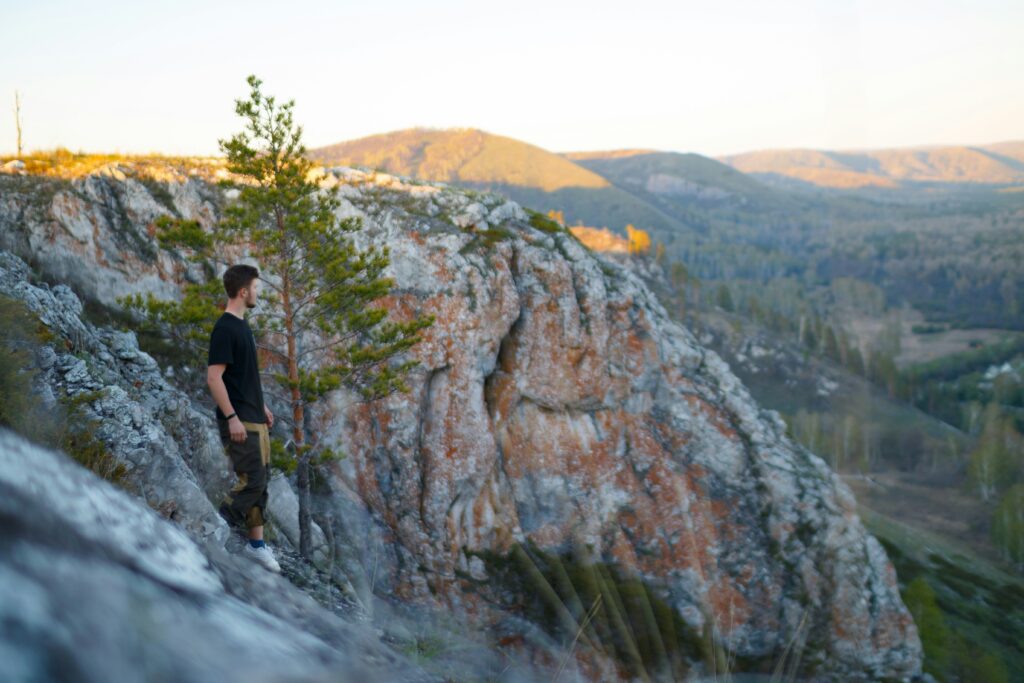 A man standing high up on a rocky mountain looking out at the view