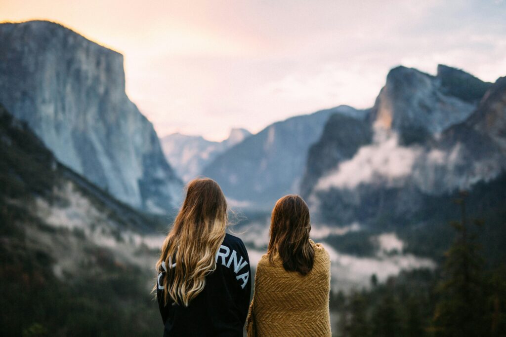 Two girls standing on a mountain with their backs to the camera